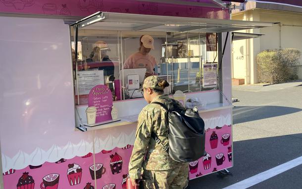 A servicemember stands outside a mobile food trailer.