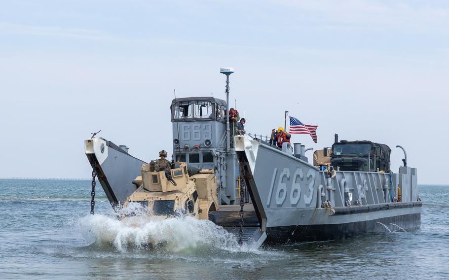 An armored vehicle gets off a small ship.