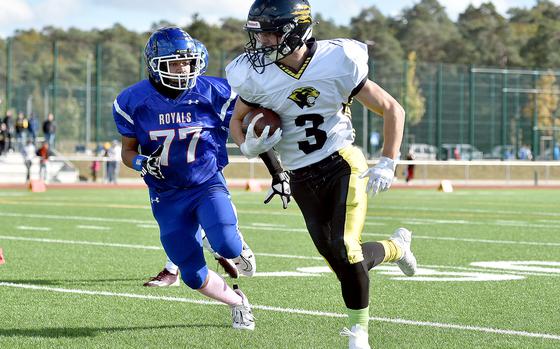 Stuttgart's Jace Holmes runs along the sideline during the Panthers' Division I semifinal against the Royals on Oct. 21, 2023, at Ramstein High School on Ramstein Air Base, Germany. Chasing is Royal defender Matthew Rutlege.