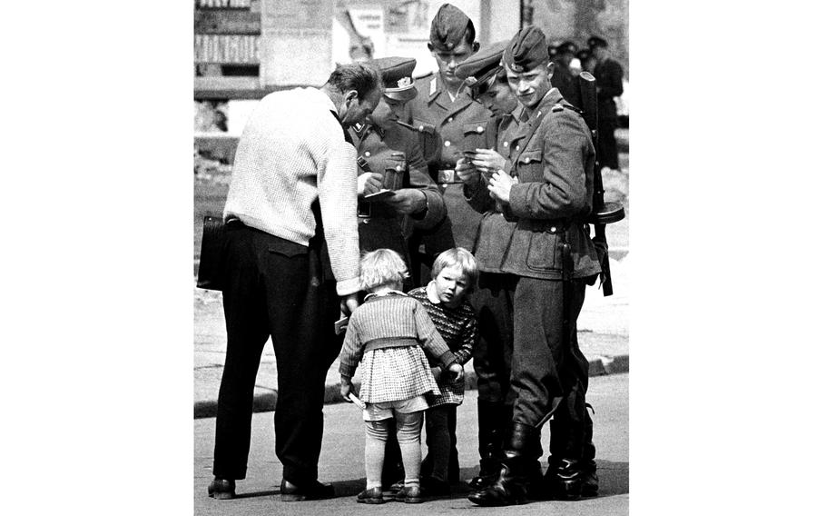 Berlin dad answers the questions of Communist border guards and keeps an eye on two restless children.