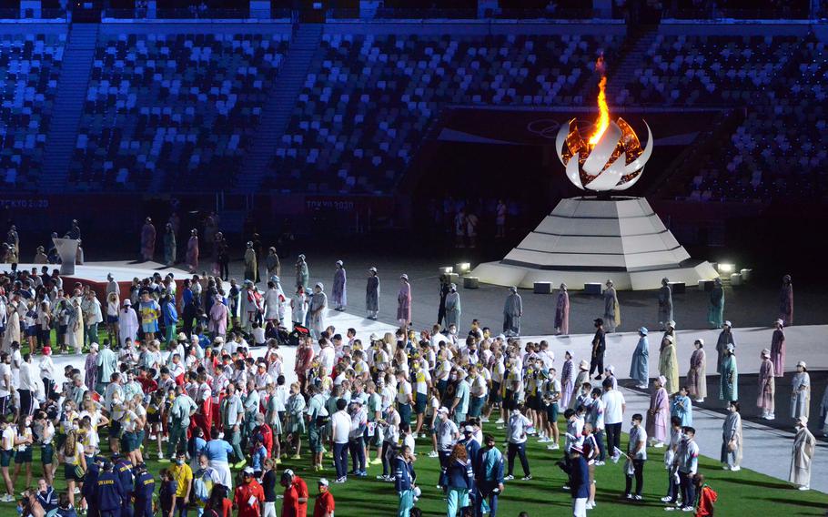 Athletes assemble near the Olympic flame during the closing ceremony of the Tokyo games, Sunday, Aug. 8, 2021. 