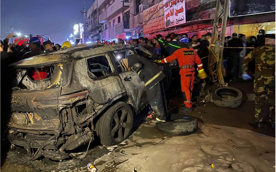 Civil defense members gather at the site of a burned vehicle targeted by a U.S. drone strike in east Baghdad, Iraq, on Feb. 7, 2024.