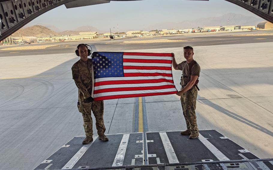 Staff Sgt. Duncan Copley, right, and another airman hold an American flag at the airport in Kabul, Afghanistan, during the evacuation of civilians from the country last year. Copley dealt with a bomb threat during one of his flights.