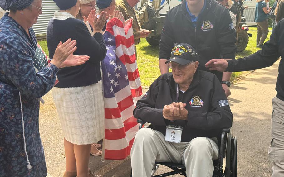 Women in WWII-era styles applaud as veteran Ray Falke passes by in Houlgate, France, on Monday, June 3, 2024.