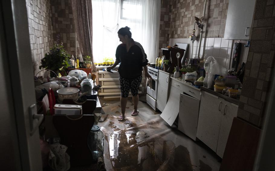 Katia Lysenko walks in the kitchen of her flood-damaged apartment in Kherson, which she traveled to by boat.