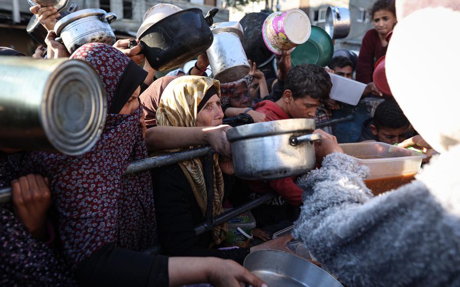 Displaced Palestinians gather to receive food donated by a charitable group in Rafah on March 12, 2024.
