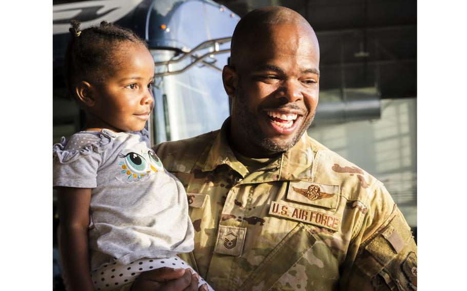 A service member holds his young daughter upon returning home from a deployment.