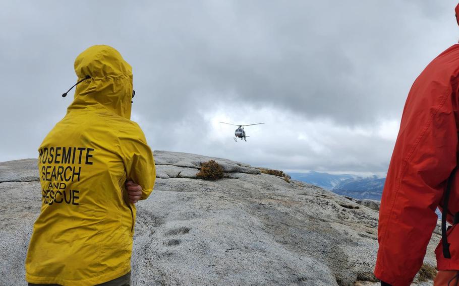 Climbers stand with a Yosemite Search and Rescue park ranger to flag down a helicopter for a medical evacuation at Yosemite National Park, California, Sept. 2, 2023. U.S. Air Force Capt. Joshua Haveman, 60th Air Evacuation Squadron flight instructor, was involved in the rescue of a climber on Half Dome after inclement weather caused unfavorable climbing conditions. 