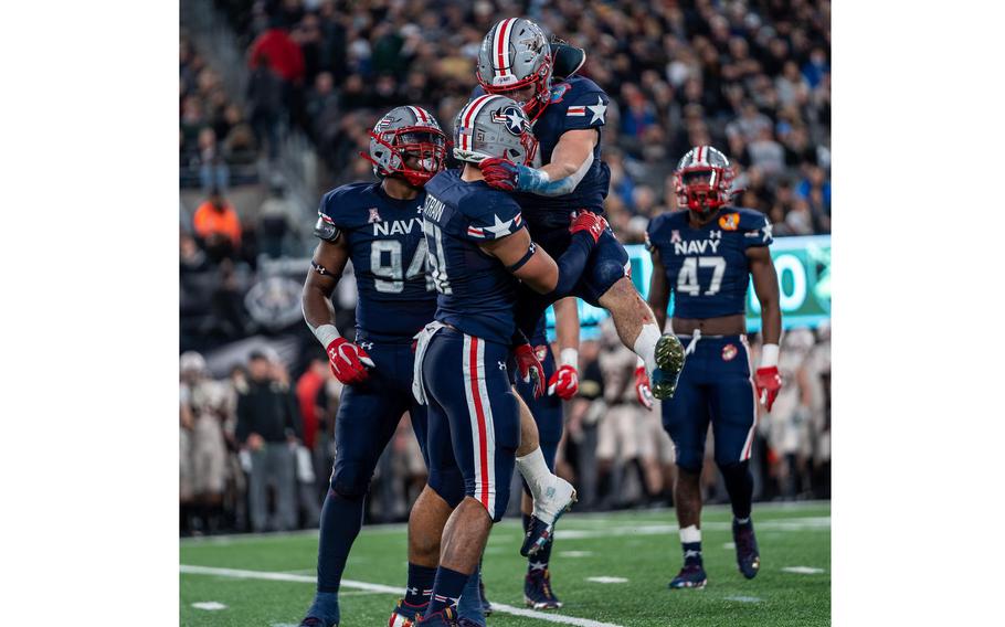 Navy players celebrate Saturday, Dec. 11, 2021, on the way to a victory against Army at MetLife Stadium in East Rutherford, N.J.