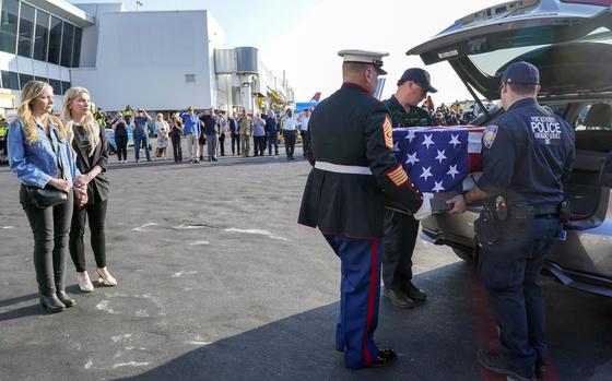 Teresa Irwin, left, sister of Marine Capt. Grady Kurpasi, watches as Marine First Sgt. Timothy La Sage, center, and Port Authority police officer place his remains into an waiting car at New York's John F. Kennedy International Airport, Friday, May 19, 2023, in New York. The remains of a U.S. Marine veteran who had been missing in Ukraine for more than a year will be returned to his family in eastern North Carolina later Friday, according to the group bringing the remains back to the U.S. (AP Photo/Mary Altaffer)