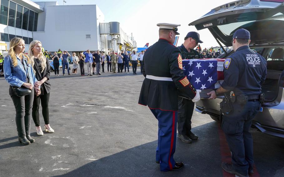 Teresa Irwin, left, sister of former Marine Capt. Grady Kurpasi, watches as Marine 1st Sgt. Timothy La Sage, center, and Port Authority police officers place his remains into a waiting car at New York’s John F. Kennedy International Airport on May 19, 2023, in New York. The remains of the Marine veteran who had been missing in Ukraine for more than a year were returned to his family in eastern North Carolina.