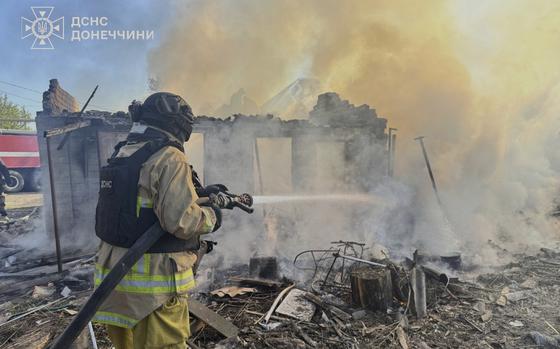 A firefighter aims a hose into a destroyed building that is smoking from a recent fire.