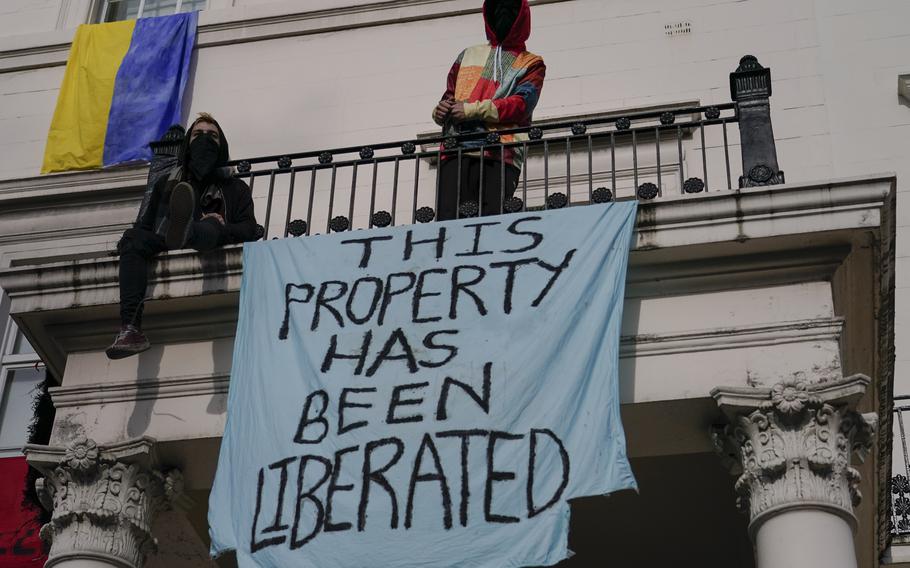 Squatters display banners and a Ukrainian flag as they occupy a building which is believed to be owned by a Russian oligarch, in London, Monday, March 14, 2022.