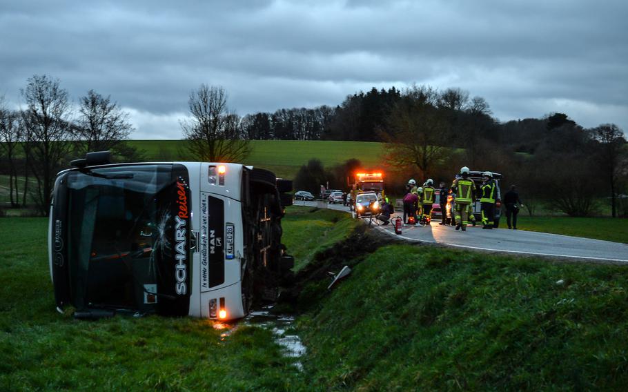 A DODEA school bus lies on the ground after heading off an embankment Friday, March 10, 2023, near Weilerbach, Germany. Sixteen students were on board, and one was taken to Landstuhl Regional Medical Center with minor injuries, authorities at the Weilerbach firehouse said.
