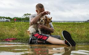 Tim McCanon sits on the road with his dogs after being rescued by the Community Fire Department during severe flooding on Friday, May 3, 2024, in New Caney, Texas.