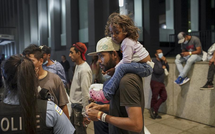 Elier Salazar Chacon, 29, carries his 3-year-old daughter Danieli Cataleya Salazar while talking with a Chicago police officer after arriving on a bus with 75 other migrants from Texas at Union Station on Aug. 31, 2022, in Chicago.