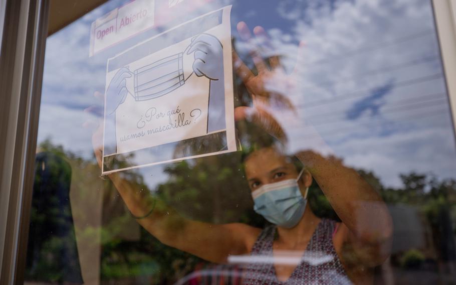 A clothing store worker poses next to a sign encouraging the use of a masks during the COVID-19 pandemic at the entrance to the store in Managua, Nicaragua, Thursday, Sept. 9, 2021.
