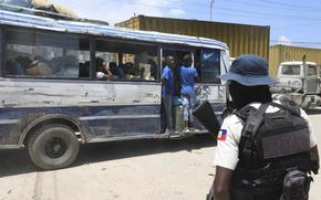 A bus passes by a police officer on patrol near the airport in Port-au-Prince, Haiti, Friday, May 24, 2024. (AP Photo/Odelyn Joseph)
