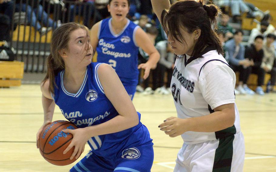 Osan's Abigail Elliott looks for room against Daegu's Hazel Bell during Friday's Korea girls basketball game. The Warriors won 28-17.