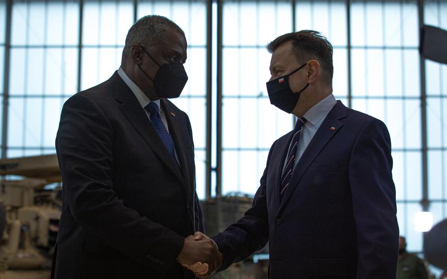 Defense Secretary Lloyd Austin, left, and Mariusz Błaszczak, minister of national defense of Poland, shake hands during a visit to Powidz Air Base, Poland, on Feb. 18, 2022. 