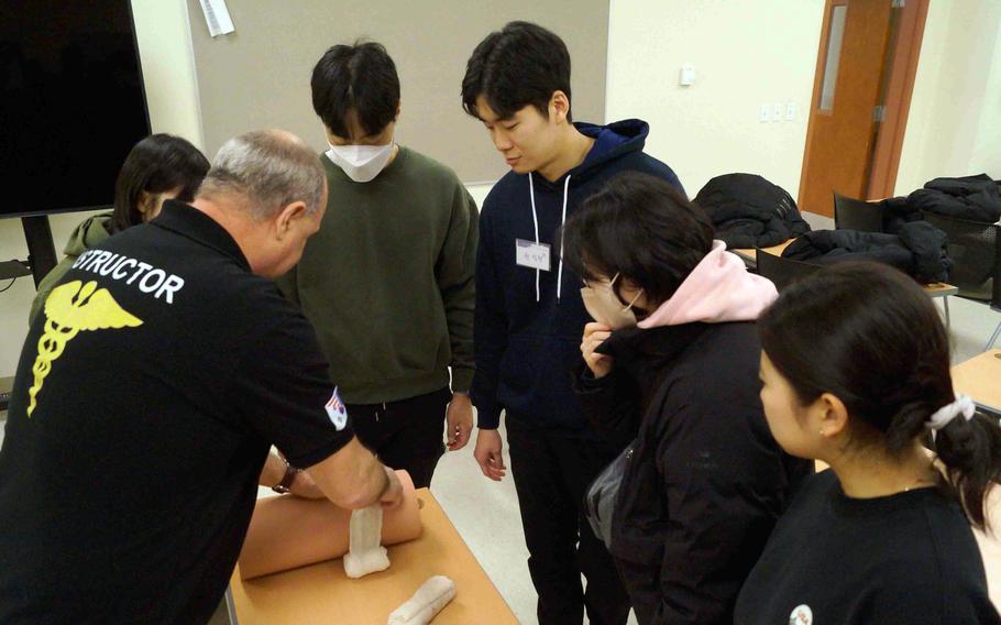Pyeongtaek University students learn the proper method of applying a tourniquet and patching and wrapping a wound during a tour of Camp Humphreys, South Korea, Jan. 17, 2024.