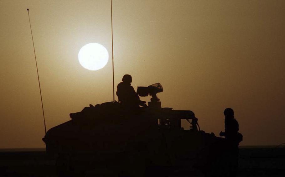 U.S. service members are silhouetted against the desert sun during the Gulf War.