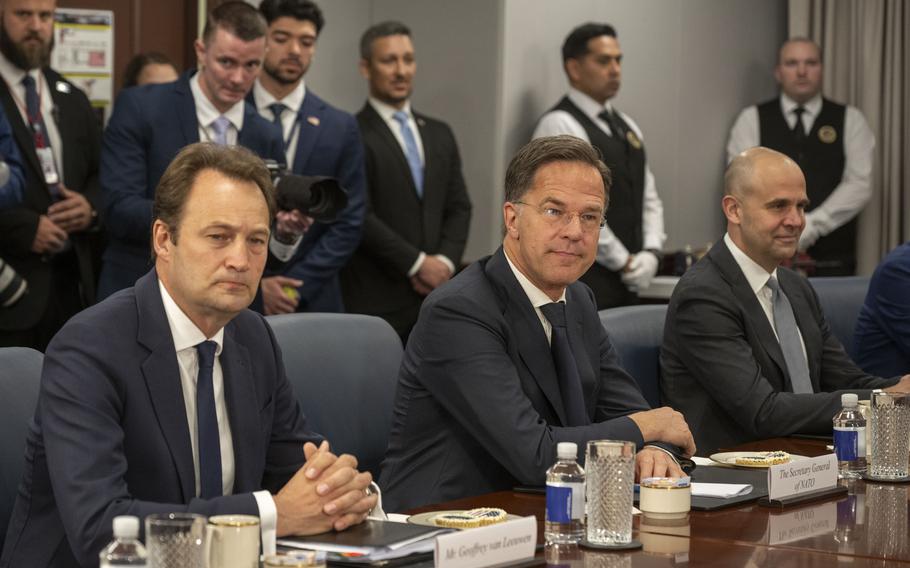Three men sit at a long table at the Pentagon