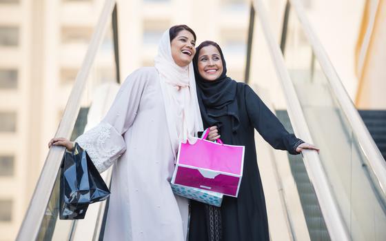 Women in traditional Muslim attire shopping outdoors.