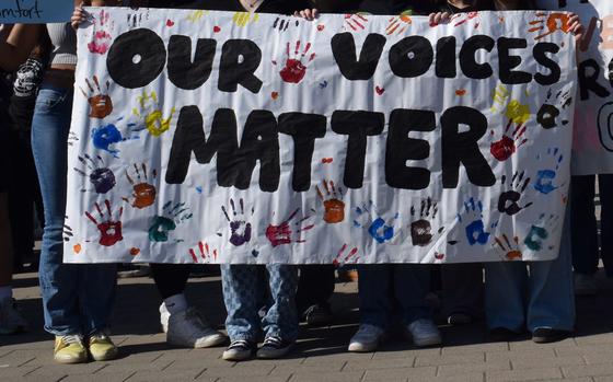 Students at Wiesbaden High School in Germany hold up a banner at a demonstration March 6, 2025. DODEA administrators in Europe and Asia are issuing letters to parents warning that students who participate in walkouts during school time will be given unexcused absences.