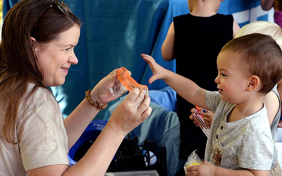 Kelly Welsh shows her 21-month-old son Sullivan Welsh a spring toy from a box of prize options while visiting informational booths at the Exceptional Family Member Program’s meet-and-greet event at Fort Leavenworth, Kan., in August 2022.