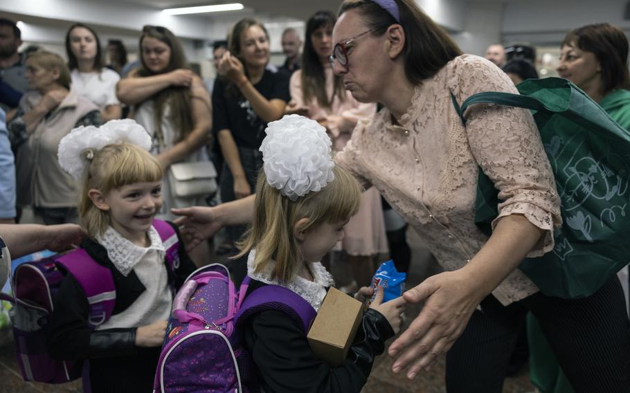 Nadia Kozyreva greets her twin 6-year-old daughters, Kateryna and Victoria, from the city of Kupyansk, as other mothers and fathers waited for their children to come out of their classrooms on the first day of school held in the underground metro station in Kharkiv, Ukraine.