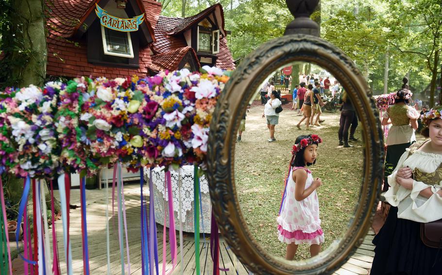 Xinyi Xie is reflected in a mirror as she walks by a booth selling garlands at the Maryland Renaissance Festival in 2015. 