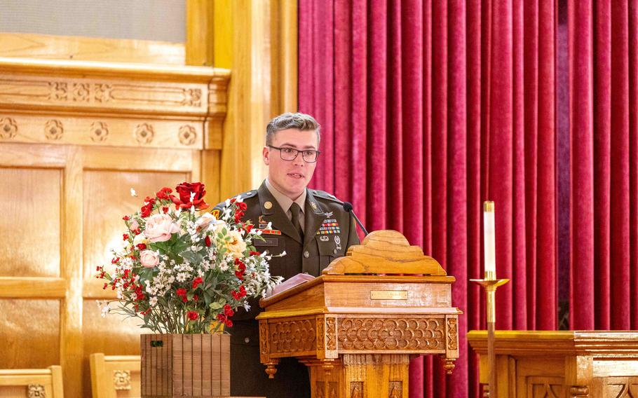 Martin speaks at a lectern, with flowers to his right and a candle to his left.