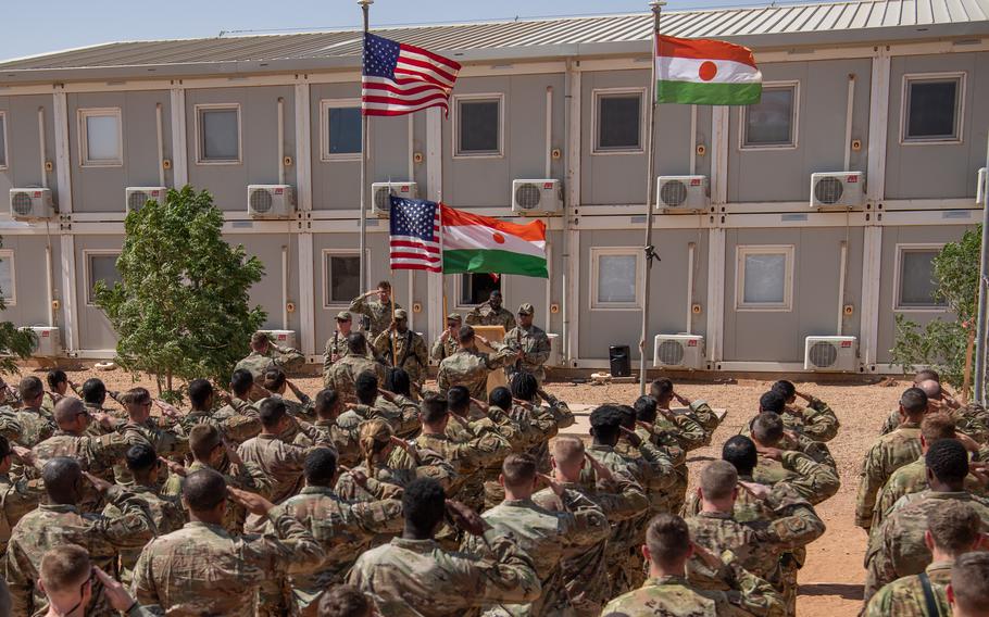 U.S. service members at Air Base 201 salute during the Nigerien and American national anthems during a Veterans Day ceremony Nov. 11, 2023, at AB 201, Niger. U.S. troops are withdrawing from Niger, ending a decade of U.S. operations against local affiliates of al-Qaida and Islamic State.