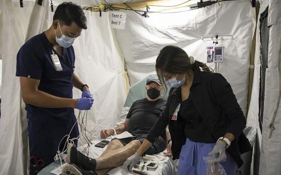 David Tran, an emergency department technician, left, prepares to put a cardiac monitor on a patient as he has his blood drawn by Jessica Smith, a registered nurse, at Scripps Memorial Hospital Encinitas on Nov. 11, 2022, in Encinitas, California. Scripps recently opened an overflow tent outside of the hospital after an increase of flu patients. (Ana Ramirez/San Diego Union-Tribune/TNS)