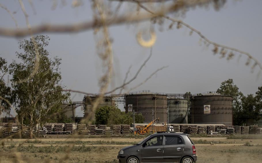 A car passes by an oil depot in New Delhi, India. The country has bought billions in Russian petroleum, as well as coal and natural gas. 
