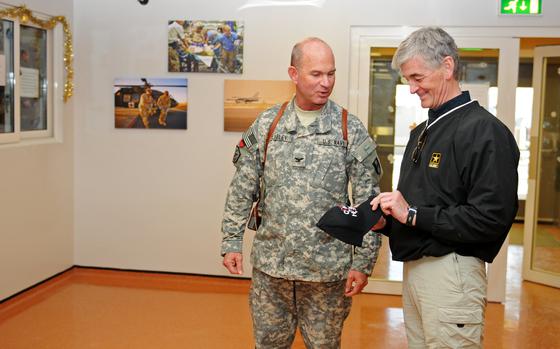 Navy Capt. Bruce Meneley of Task Force Medical- South and NATO Role 3 Multinational Hospital commander, give a “Combat Hospital” hat to Army Secretary Army Secretary John McHugh at Kandahar Airfield, Afghanistan, on Dec. 14, 2011. “Combat Hospital” was a Canadian television show that featured medical units in the warzone.  (Credit: Photo by US Army Sgt. Amanda M. Mills)
