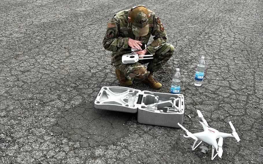 A soldier sets up a drone on pavement.