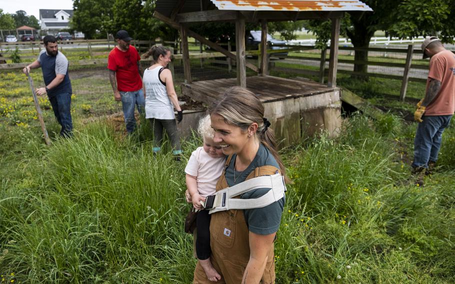 Kayla Arestivo, a co-founder with Trails of Purpose, watches as volunteers help move bails of hay on May 20, 2023, during a clean up event for Trails of Purpose ahead of the opening of their new location in Virginia Beach. Trails of Purpose provides services for 100 people per week.