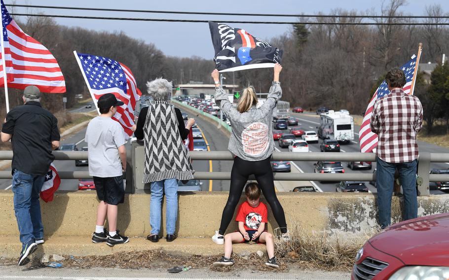 People stand on Georgetown Pike to watch the convoy pass on Sunday. 