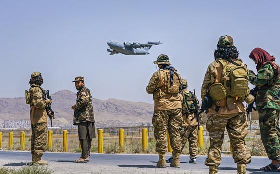 KABUL, AFGHANISTAN -- AUGUST 29, 2021: A C-17 Globemaster takes off as Taliban fighters secure the outer perimeter, alongside the American controlled side of of the Hamid Karzai International Airport in Kabul, Afghanistan, Sunday, Aug. 29, 2021. (MARCUS YAM / LOS ANGELES TIMES)
