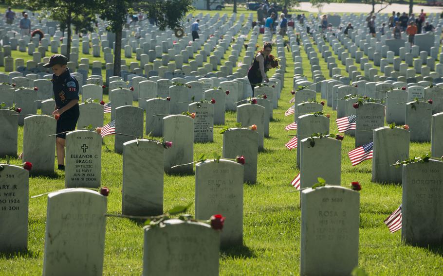 Volunteers on May 25, 2015, place roses on headstones in Section 60 of Arlington National Cemetery, Va. 