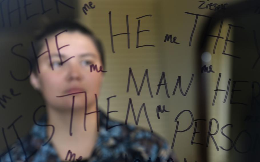 Senior Airman Max Miller looks into a mirror at home in Waianae, Hawaii, on which pronouns are written. The Air Force recently authorized the use of gender pronouns in official signature blocks.