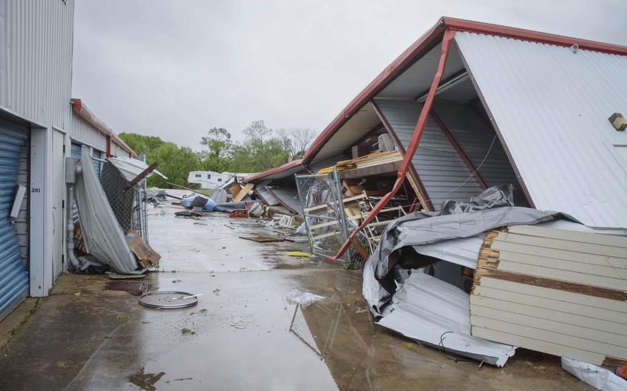 A collapsed structure, debris and standing water on the ground.