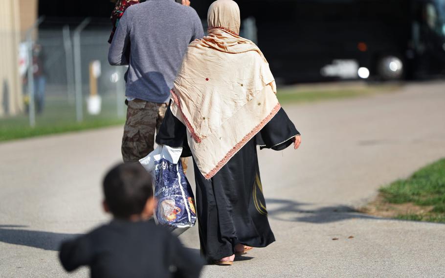 An Afghan family walks to a bus to take them back to their community at the Operation Allies Welcome Afghan evacuees settlement Thursday, Oct. 14, 2021, at Camp Atterbury in Edinburgh, Ind.