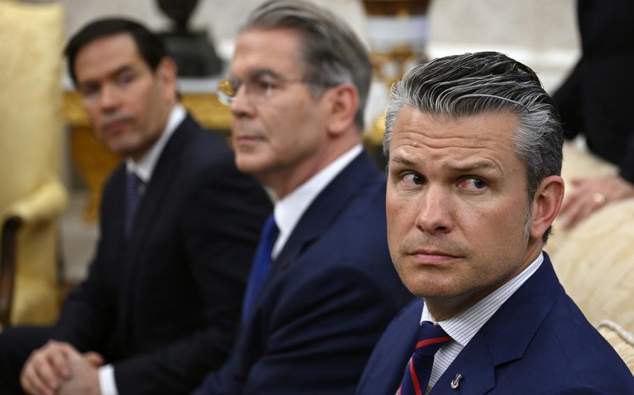 An in-focus Defense Secretary Pete Hegseth on the right with two out-of-focus officials next to him, one of whom is Secretary of State Marco Rubio.