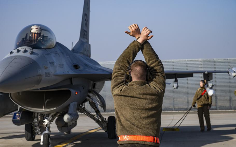 U.S. Airman 1st Class Alex Coloumbe, 480th Expeditionary Fighter Squadron dedicated crew chief, marshals an F-16 Fighting Falcon aircraft near Fetesti, Romania, Feb. 17, 2022. Romania is one of the countries the U.S. has sent additional troops to on a deployment to reassure NATO allies wary of Russia.