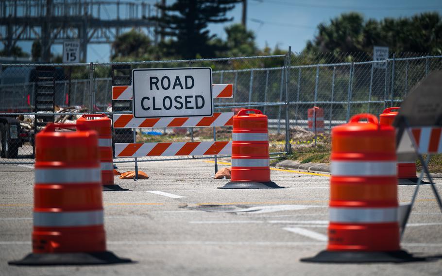 A road lined with traffic barriers and a sign reading “road closed.”