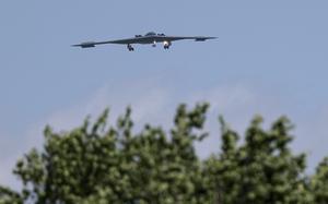 A stealth bomber flies over the treeline on its way home.
