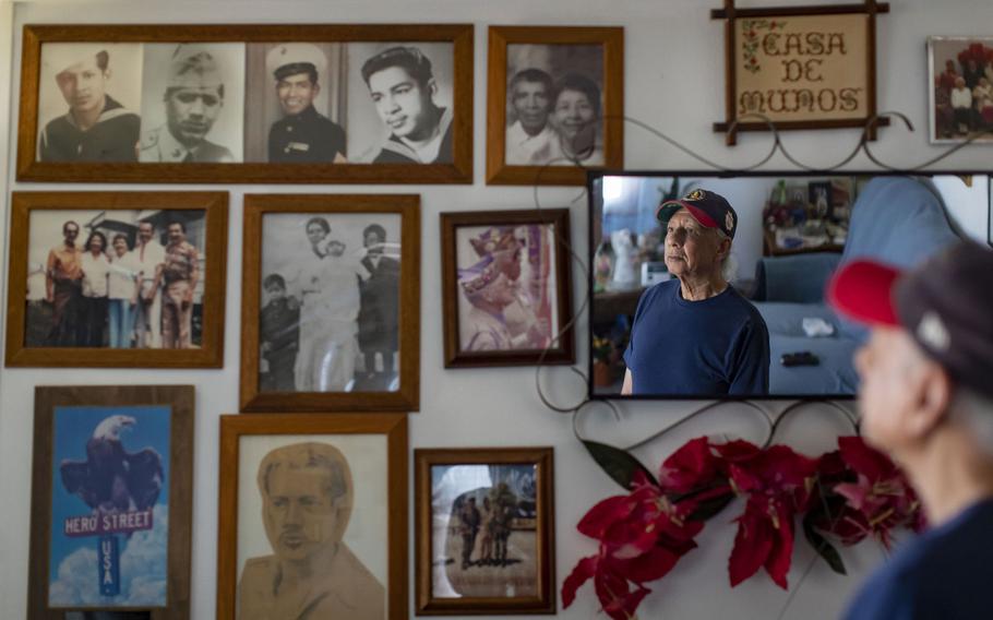 Richard Munos looks at photos in his parents' home on Hero Street of the many family members who have served in the armed forces.